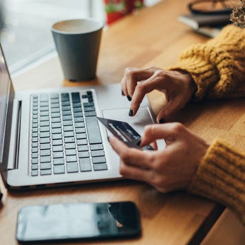 close up of person holding a credit card and typing on a computer
