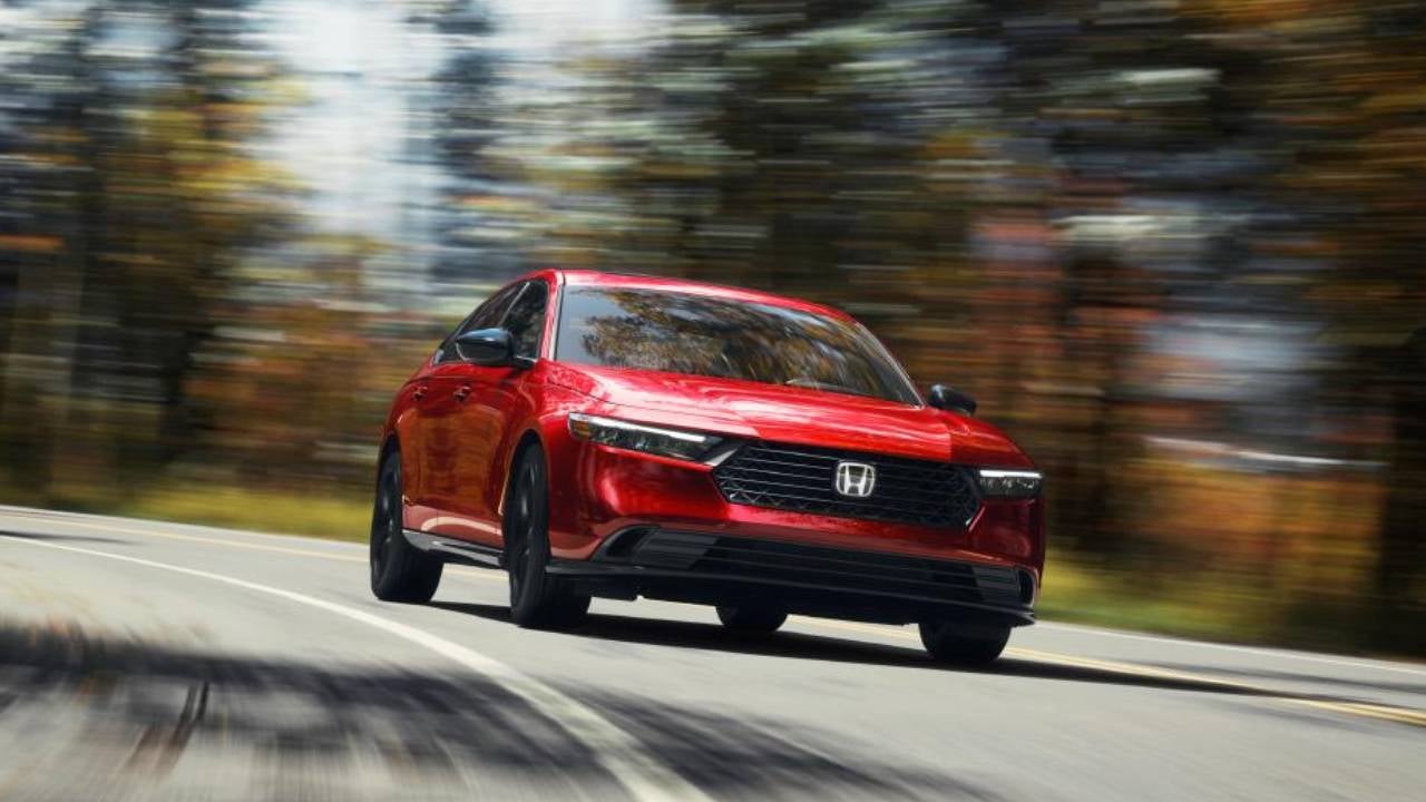 A red Honda accord driving on a forested road