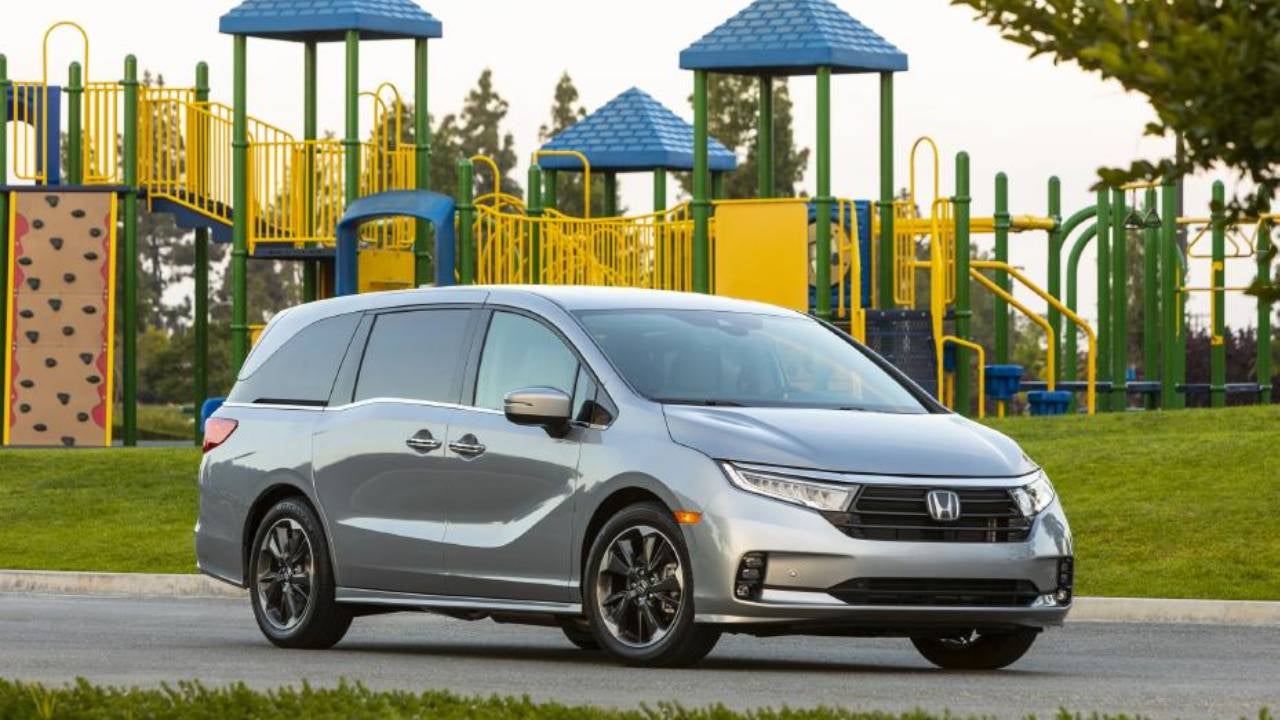 A silver Honda Odyssey parked in front of a playground