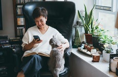 woman sitting in a chair at home and looking at her phone