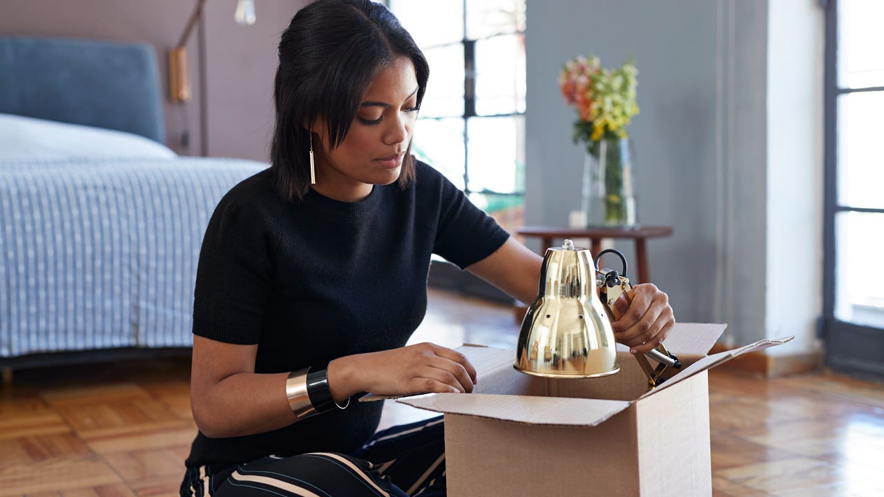 young woman opening a box with a lamp