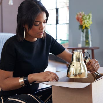 young woman opening a box with a lamp