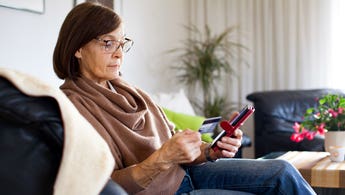 woman sitting on the couch and looking at her phone and credit card