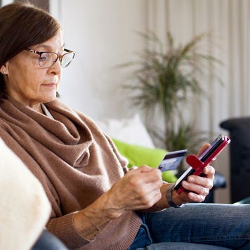 woman sitting on the couch and looking at her phone and credit card