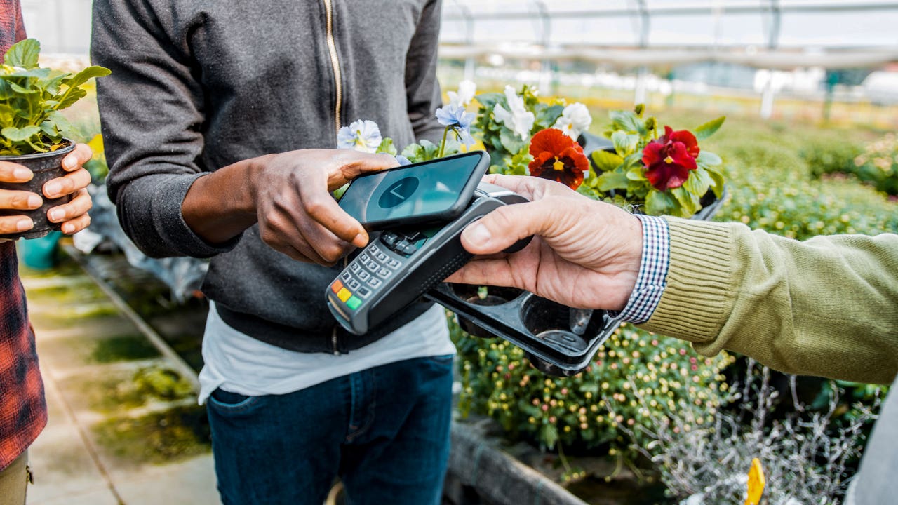 close up of man buying flowers and using mobile payment