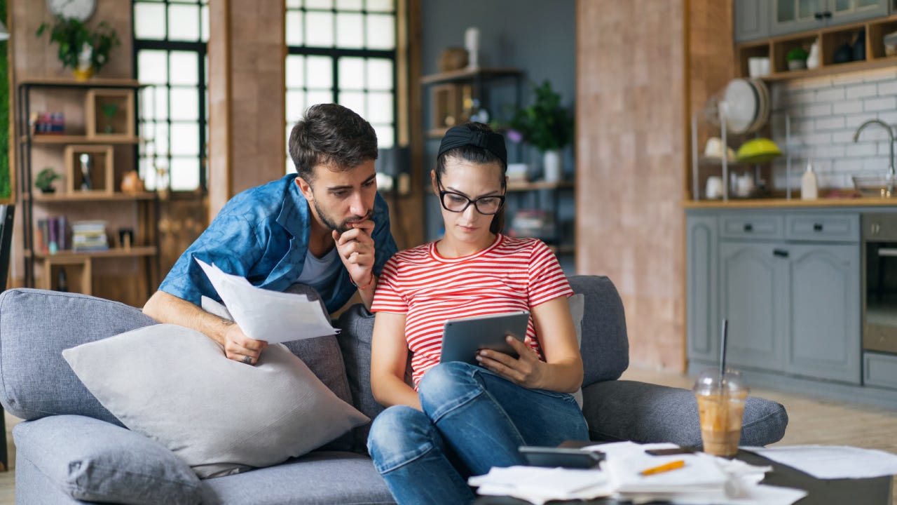 Couple calculating bills at home using tablet and calculator