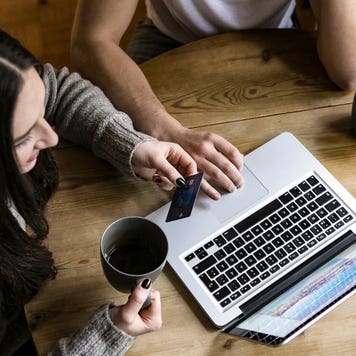 couple drinking coffee and using a credit card while on their laptop
