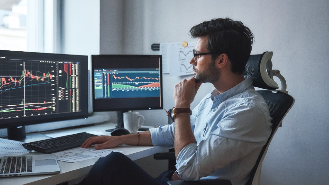 A man trades stocks on two monitors in his office