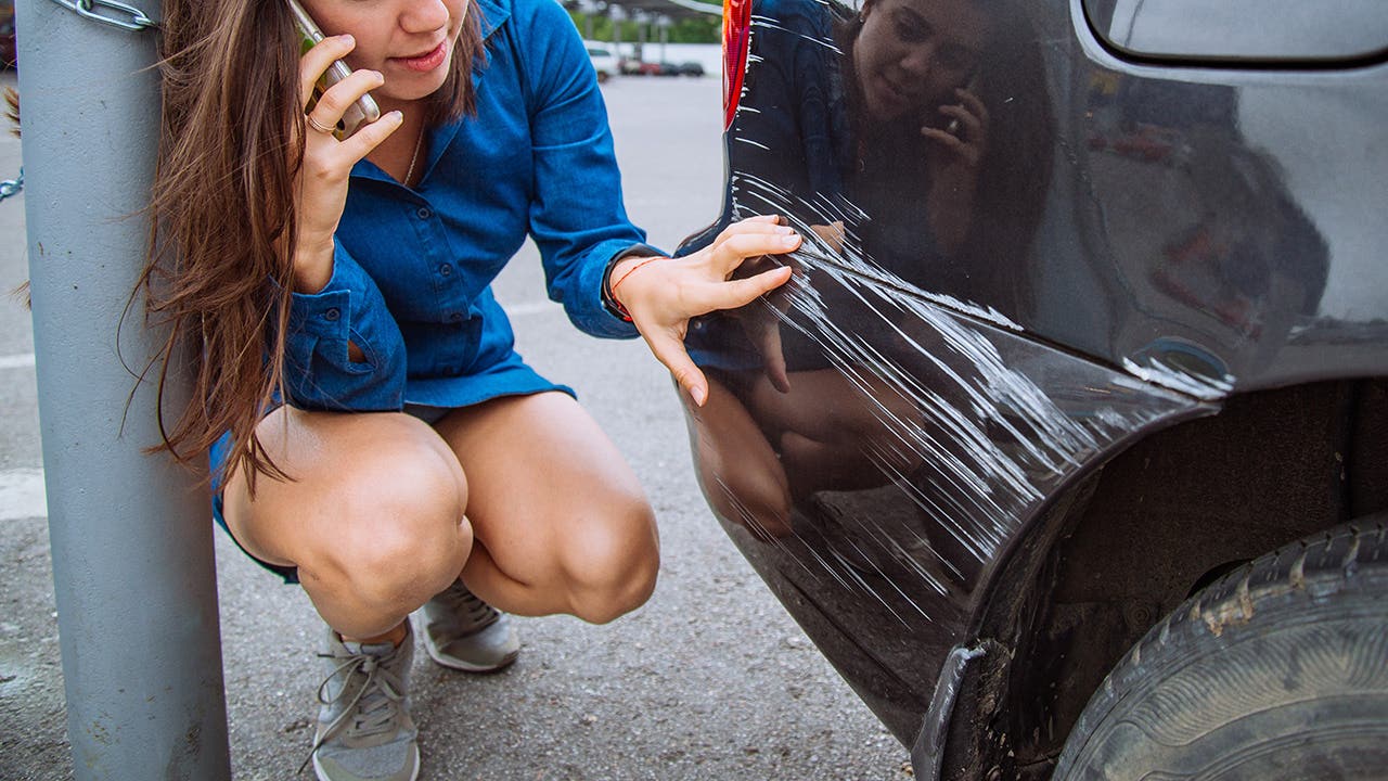 woman on the phone looking at damaged car