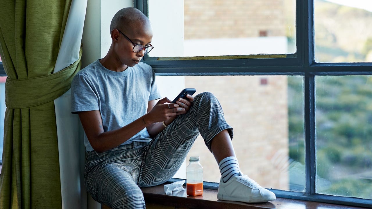 woman sitting by the window and looking at her phone