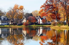 Fall view of private houses neighborhood with classic american middle class homes and colorful trees along a pond reflected in a water. Tenney Park, Madison, WI.