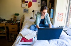 College student works on laptop in a dorm room