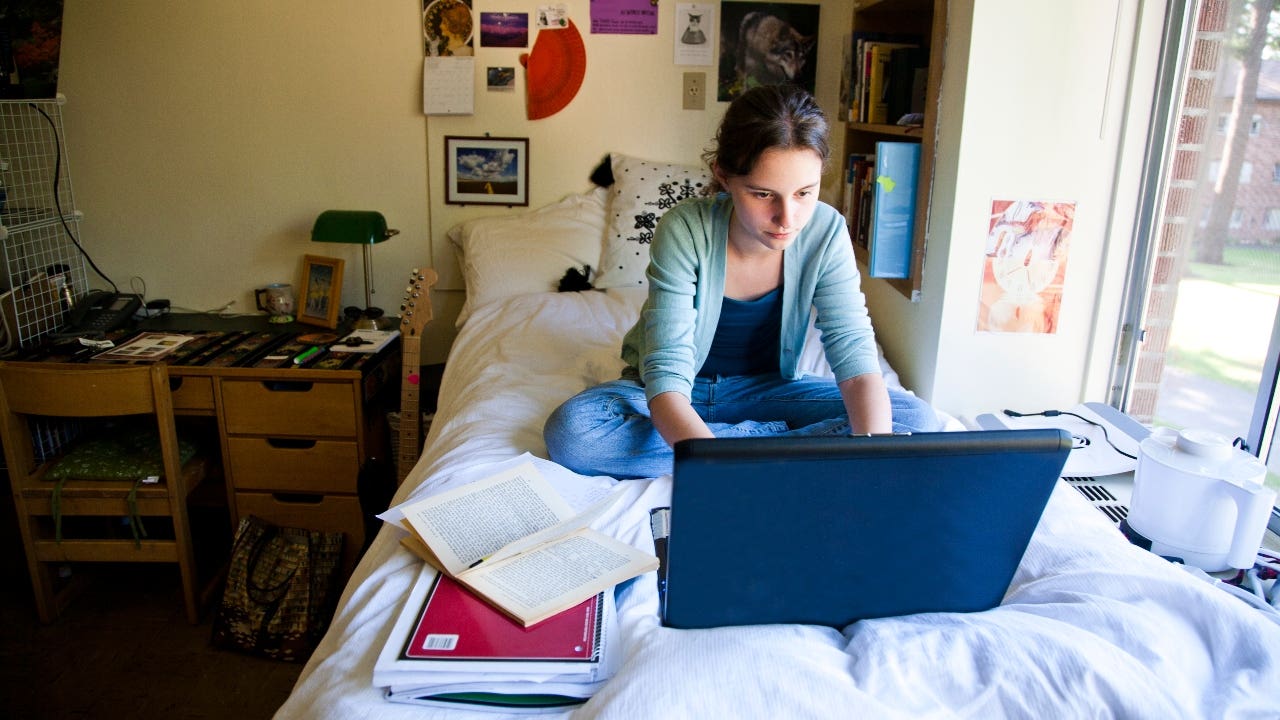 College student works on laptop in a dorm room