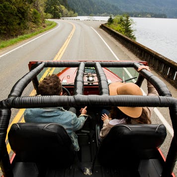 a couple in a convertible jeep driving down the road