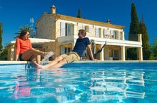 Couple sitting by a pool in front of a house