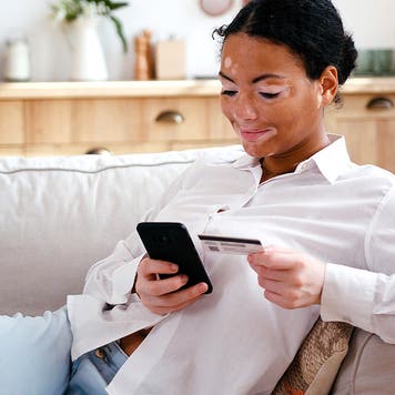 woman with vitiligo using phone and credit card