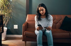 woman sitting on her couch and looking at her phone and credit card