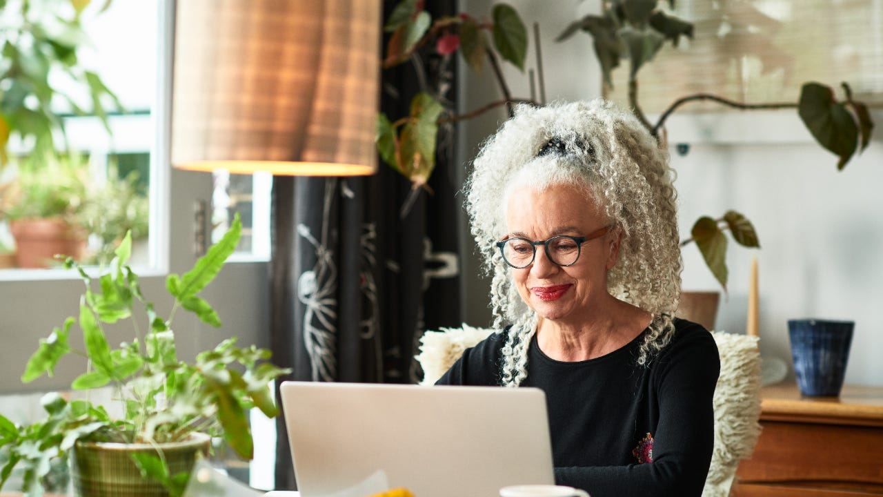 A woman invests from home on her laptop computer