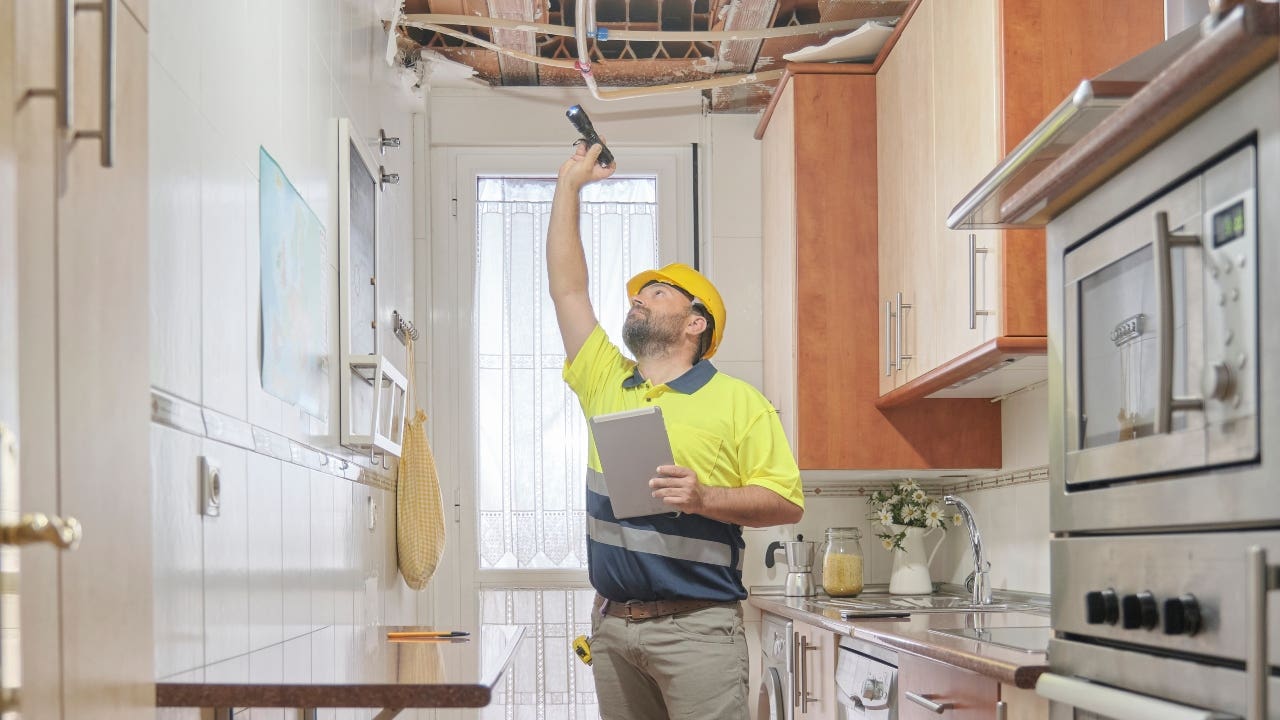 A contractor evaluates a damaged ceiling
