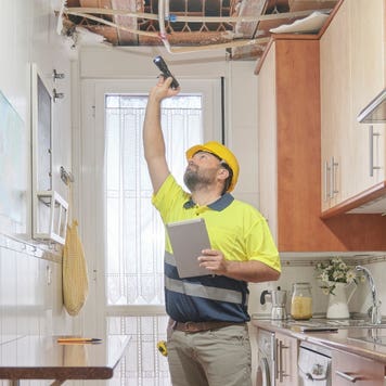 A contractor evaluates a damaged ceiling