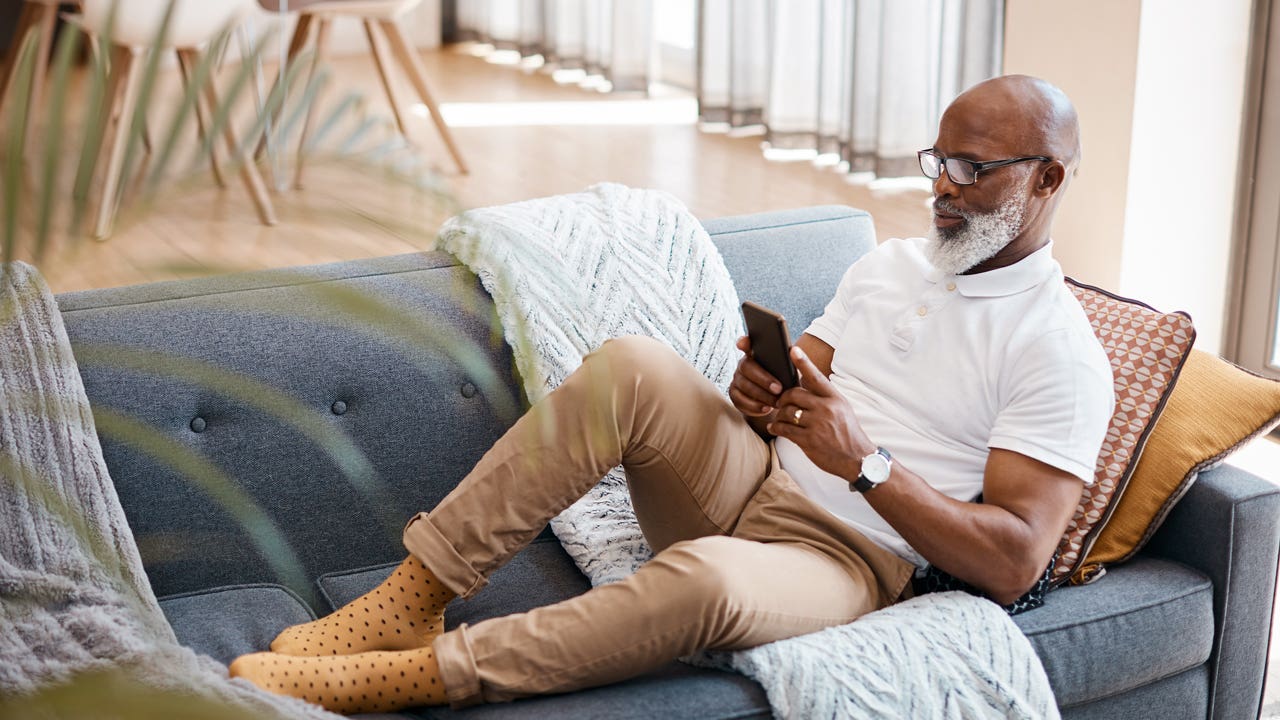 man sitting on the couch and looking at his phone