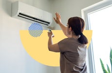 Woman using a remote to adjust an air conditioner's settings