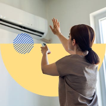 Woman using a remote to adjust an air conditioner's settings