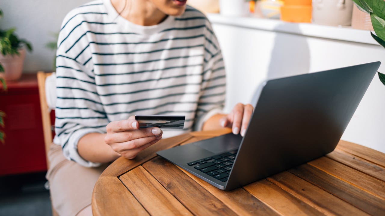 adult holding a credit card while on a computer