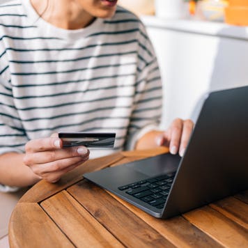 adult holding a credit card while on a computer