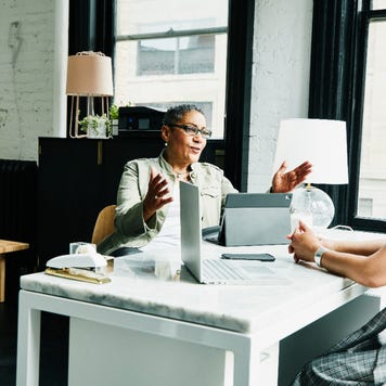 A financial advisor works with a woman client from her desk