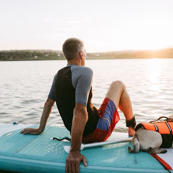 man sitting on surf board on lake