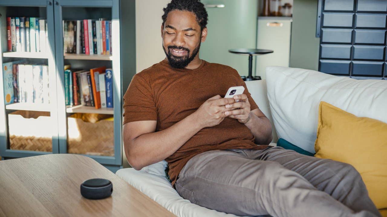 Person sitting on a couch staring at their smart home device