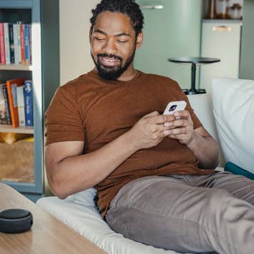 Person sitting on a couch staring at their smart home device