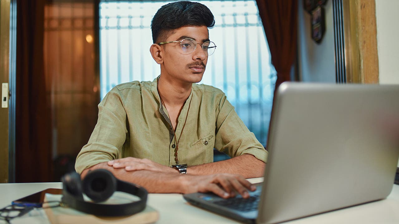 Teenage boy doing homework using laptop