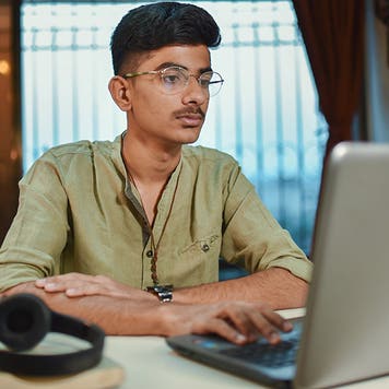 Teenage boy doing homework using laptop