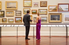 A couple looks at framed pictures on a gallery wall
