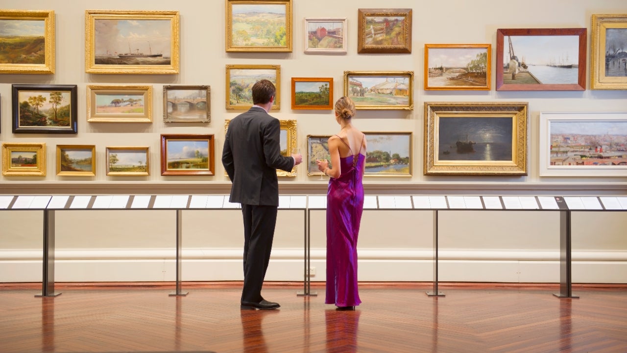 A couple looks at framed pictures on a gallery wall