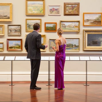 A couple looks at framed pictures on a gallery wall