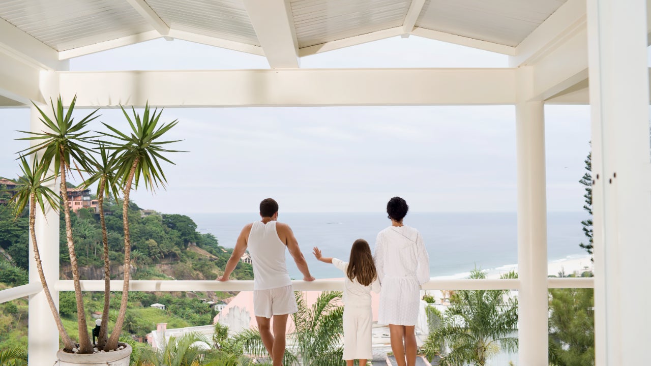 A family looks out to the sea from their house's balcony