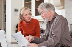 An older couple looks at their bills in the kitchen