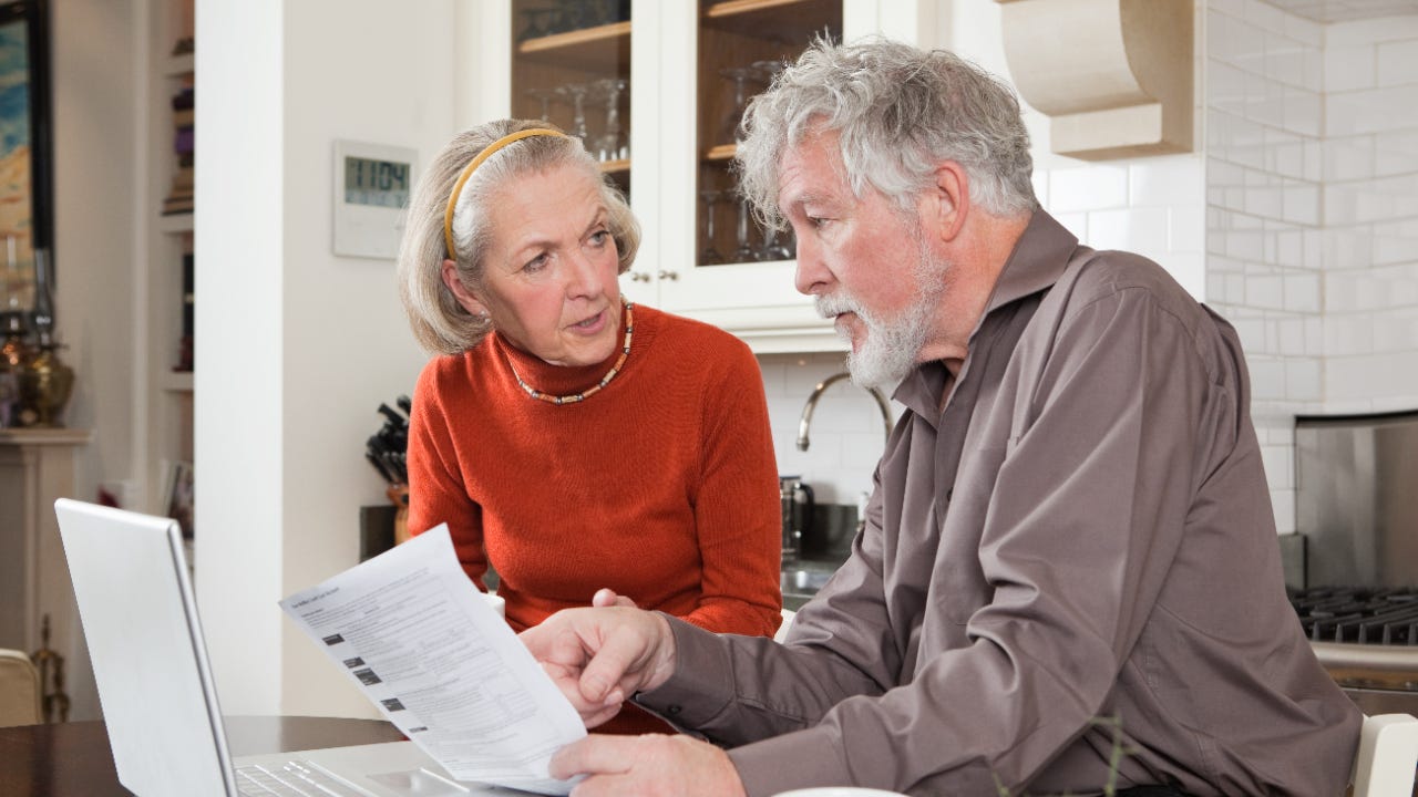 An older couple looks at their bills in the kitchen