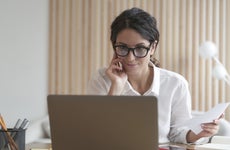 A woman smiles while looking at her laptop computer