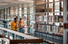Two students walk through college library