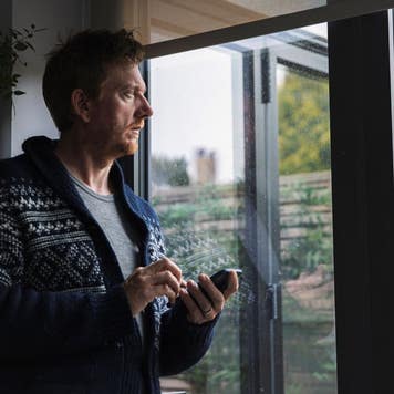 Man on his phone looking out window at rain