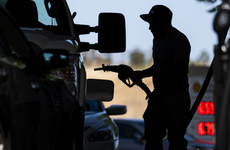 A customer holds a fuel nozzle at a Shell gas station in California