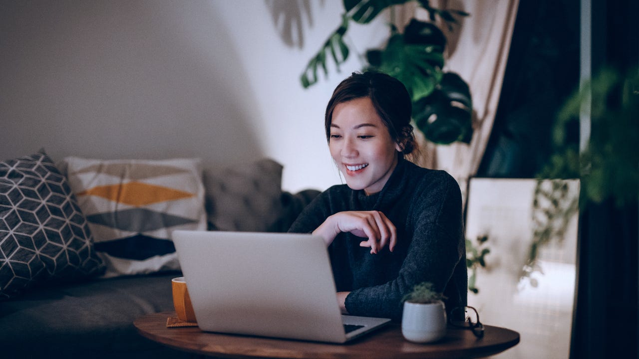 Happy woman sitting in her apartment using a laptop