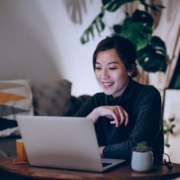 Happy woman sitting in her apartment using a laptop