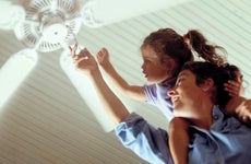 Person with a child on their shoulders, grasping ceiling fan string