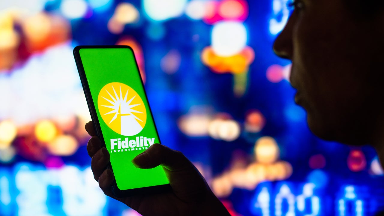 A man holds a phone with a Fidelity logo on it