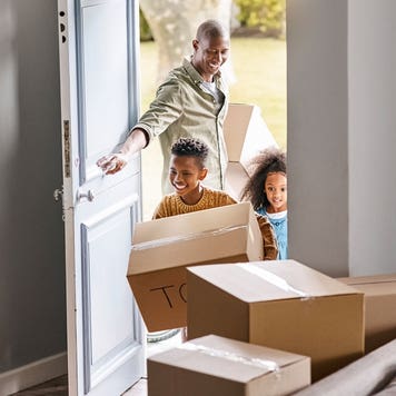 family opening the door and walking into a room with moving boxes
